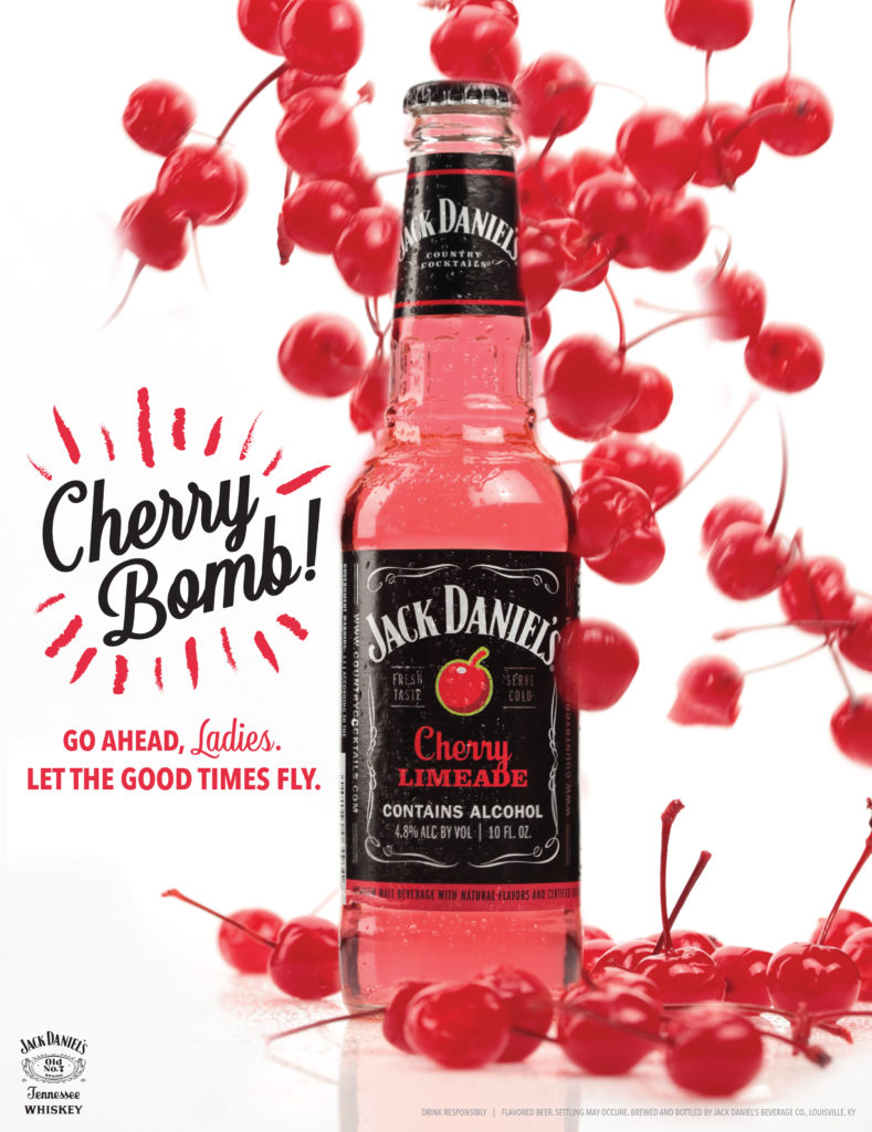 advertisement for Jack Daniel's Cherry Limeade drink. Red cherries flying at bottle on white background